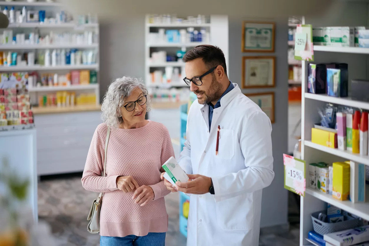 Senior woman consulting with her pharmacist before buying a medicine in drugstore.
